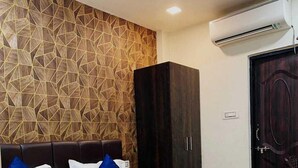 A modern hotel room with a geometric-patterned wall, a dark wooden bed with blue and white bedding, and a wardrobe. - Hotel Happy Stay  (Bhopal)