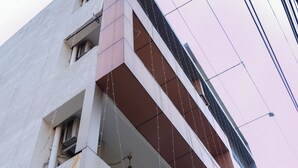 A multi-story building with balconies and hanging plants. - Hotel Happy Stay  (Bhopal)