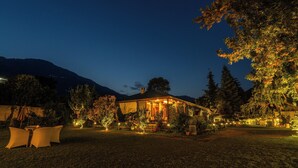 A cozy, well-lit outdoor area with a dining set and a building with a porch. - Smile Resort (Bhuntar)