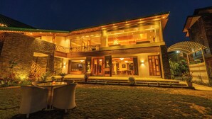 A two-story house with a balcony, a dining area, and a well-lit entrance. - Smile Resort (Bhuntar)