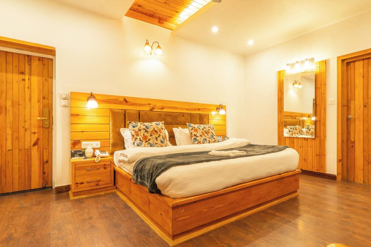 A bedroom with a wooden bed, nightstands, a mirror, and a wooden floor.