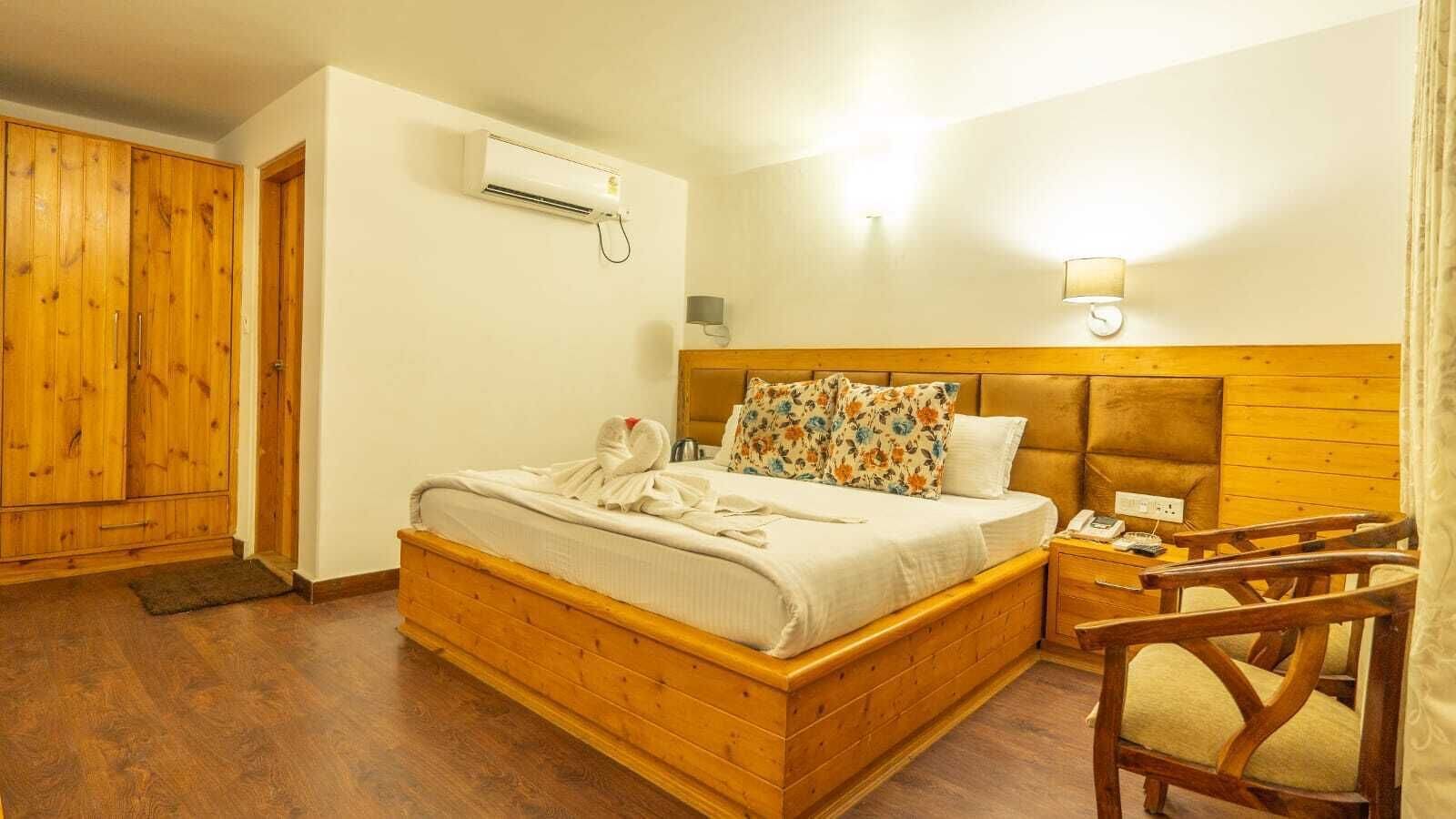 A wooden bed with a headboard, a bedside table with a lamp, and a wooden wardrobe.
