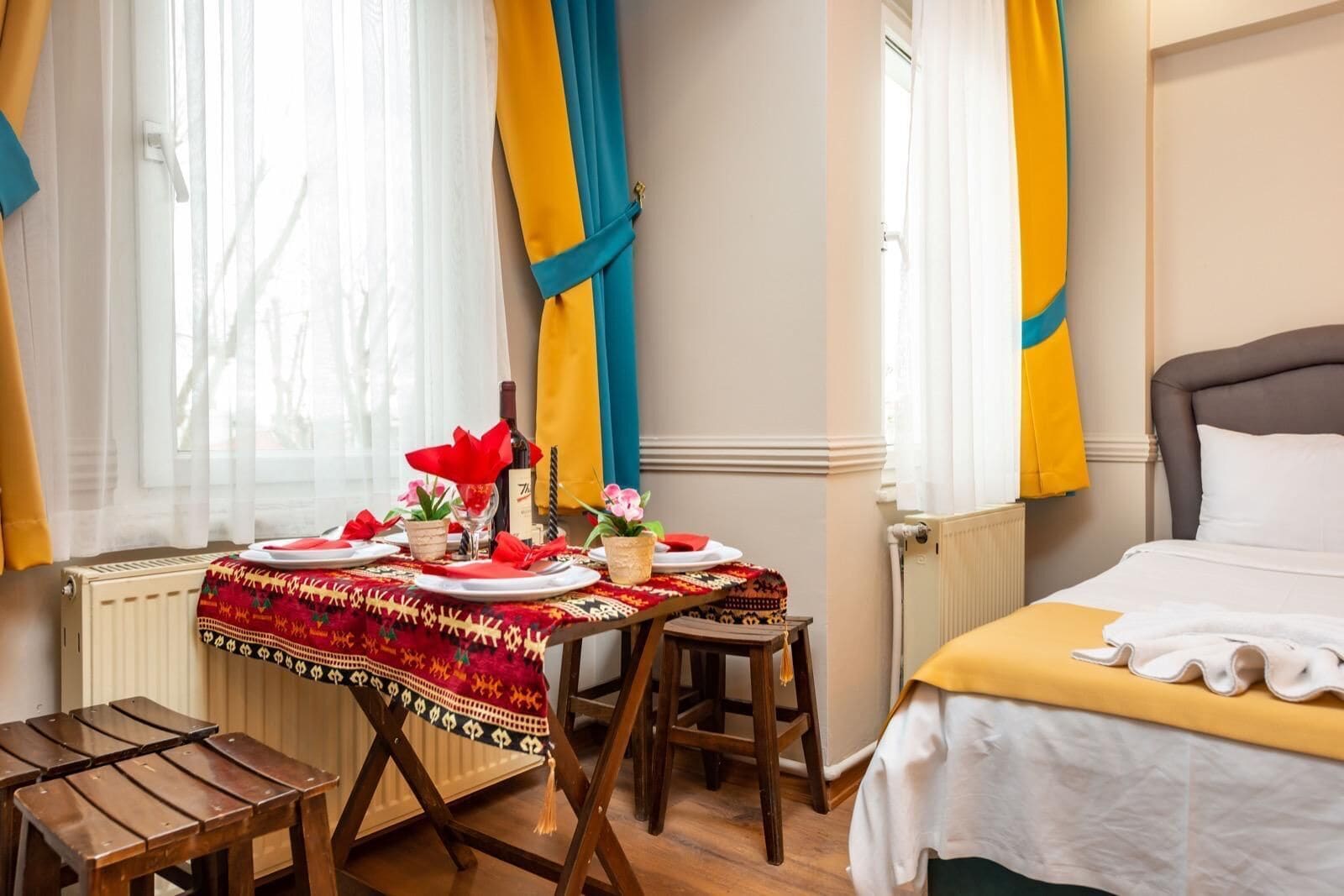 Ein Hotelzimmer mit einem Bett, einem Esstisch für zwei Personen und einem kleinen Holzschemel.