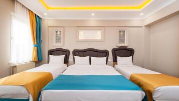 A hotel room with three beds, a large window with curtains, and a ceiling with recessed lighting.