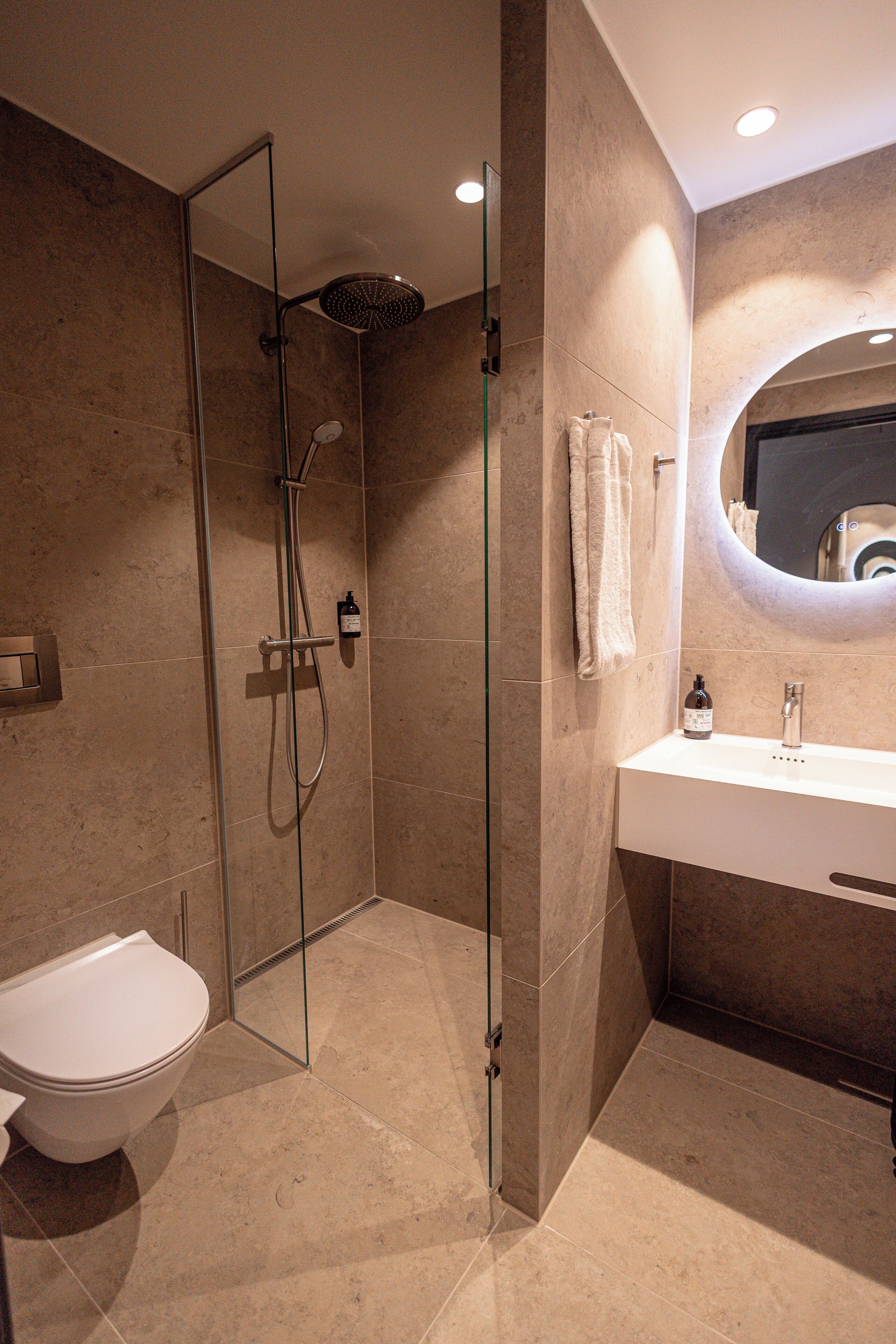 A modern bathroom with a glass-enclosed shower, a white sink, and a toilet.
