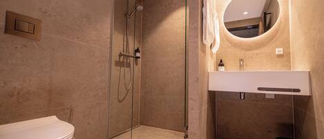 Un baño moderno con ducha de vidrio, inodoro blanco y tocador con espejo.