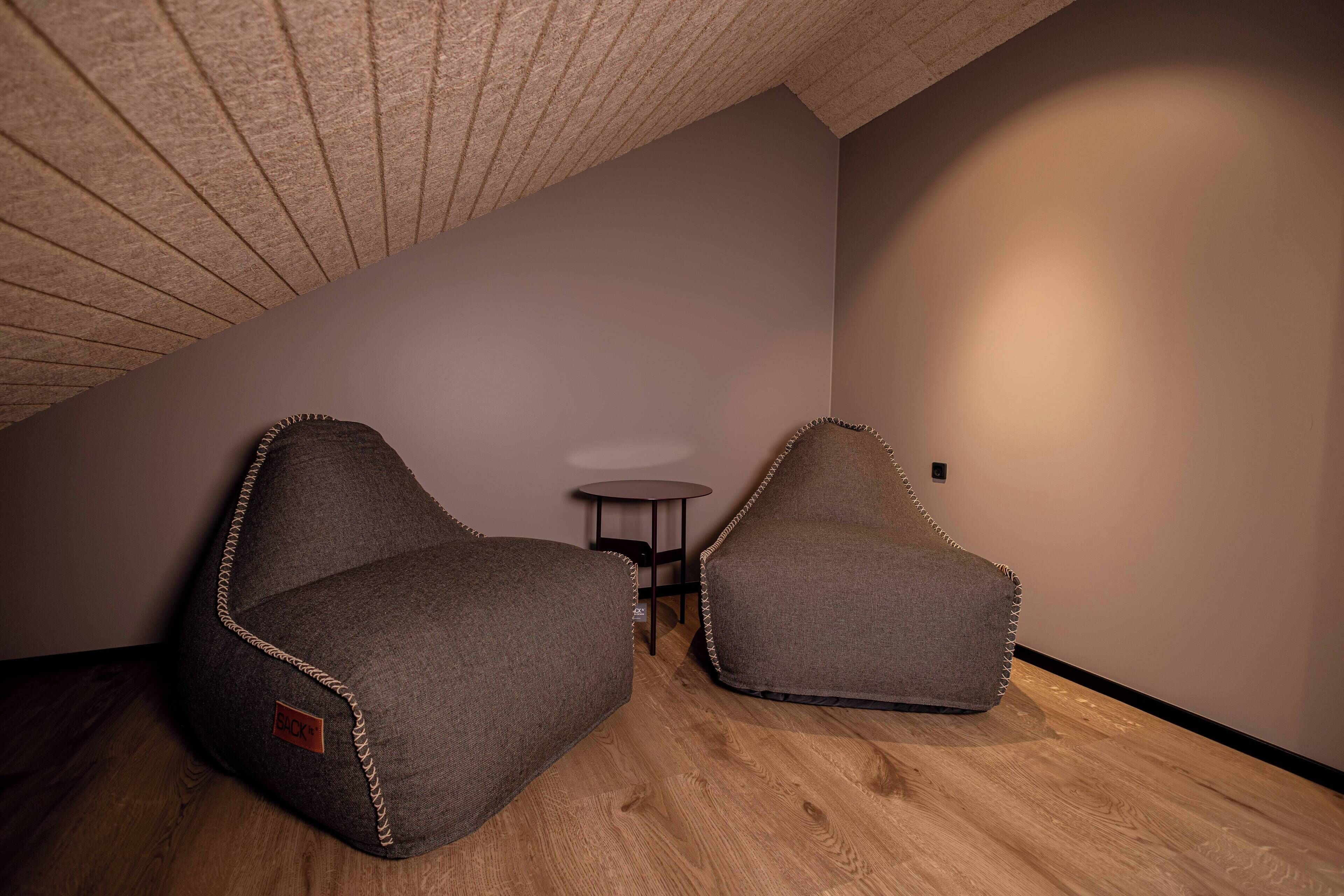 A room with two bean bag chairs, a small round table, and a sloped ceiling.