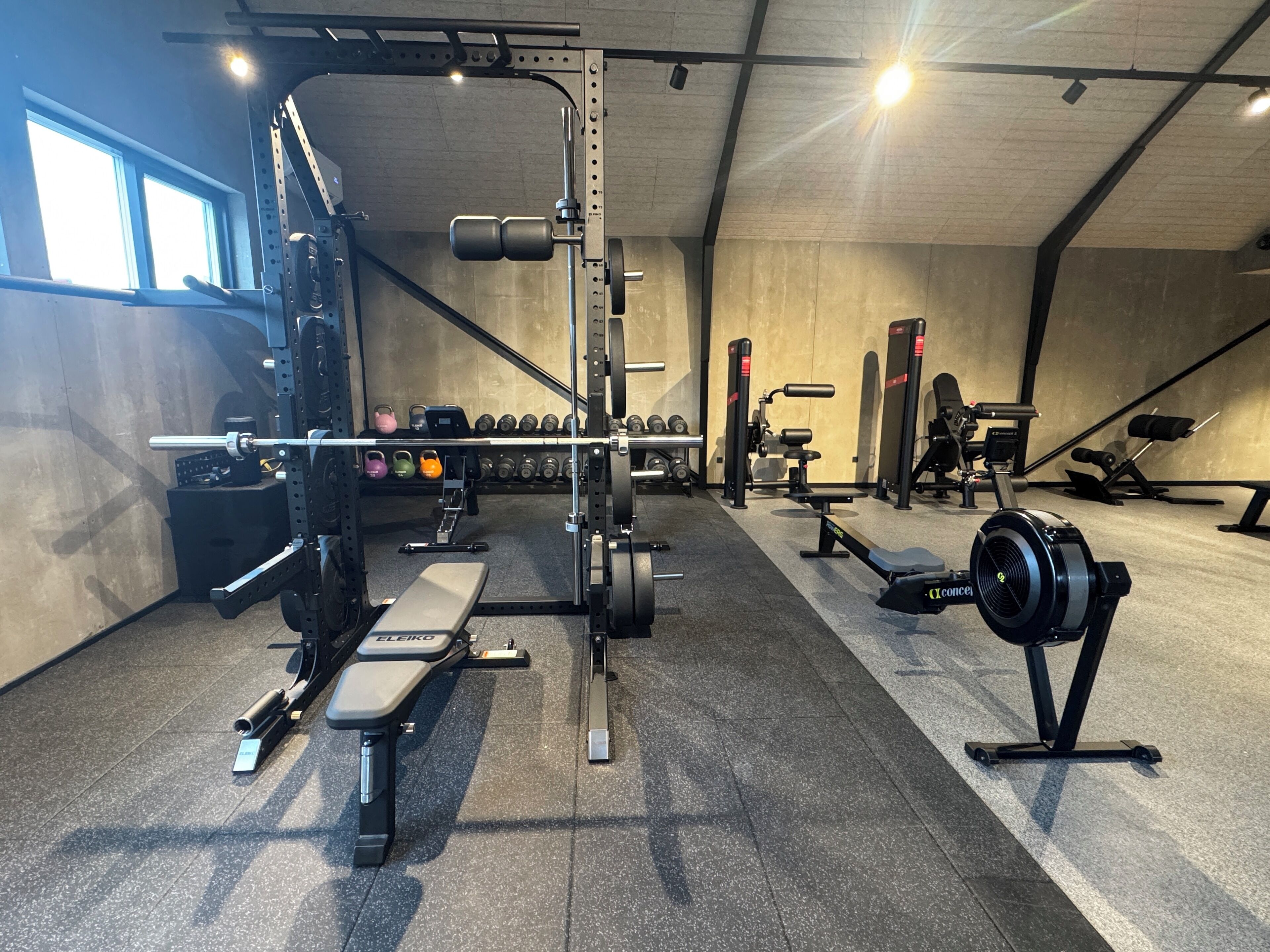 A gym with weightlifting equipment, benches, and dumbbells.