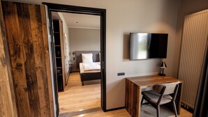 Une chambre d’hôtel avec un bureau en bois, une chaise, un lit, une télévision et une armoire.