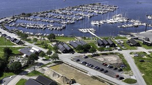 Vue aérienne d’une marina où sont amarrés des bateaux, d’un terrain de golf et d’un parking.