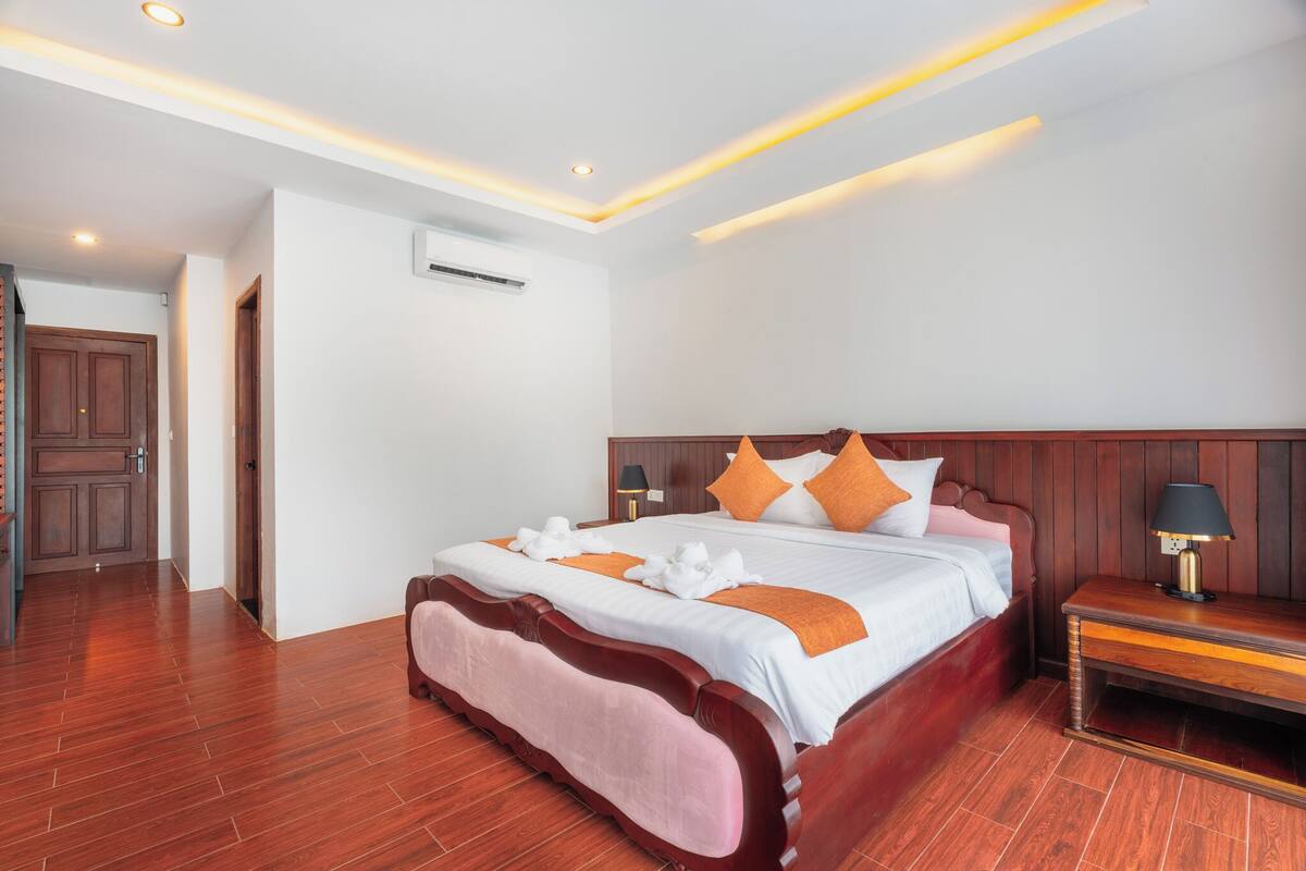 Een hotelkamer met een houten bed, witte muren en een houten vloer.