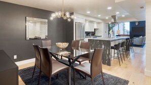 A modern kitchen with a central island, dark walls, and a chandelier.