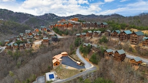 Eine Lodge mit mehreren Holzhäuschen, einem zentralen Gebäude mit einer breiten Auffahrt und einer hügeligen Landschaft im Hintergrund.
