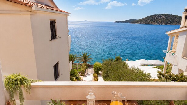 Ein Balkon mit einem für das Frühstück gedeckten Tisch, mit Blick auf das Meer.