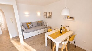 Ein modernes Wohnzimmer mit einer Couch, einem Esstisch, Stühlen und einer Pendelleuchte.