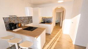 Une cuisine moderne dotée d’un îlot central, de meubles blancs et d’un crédence décorée.
