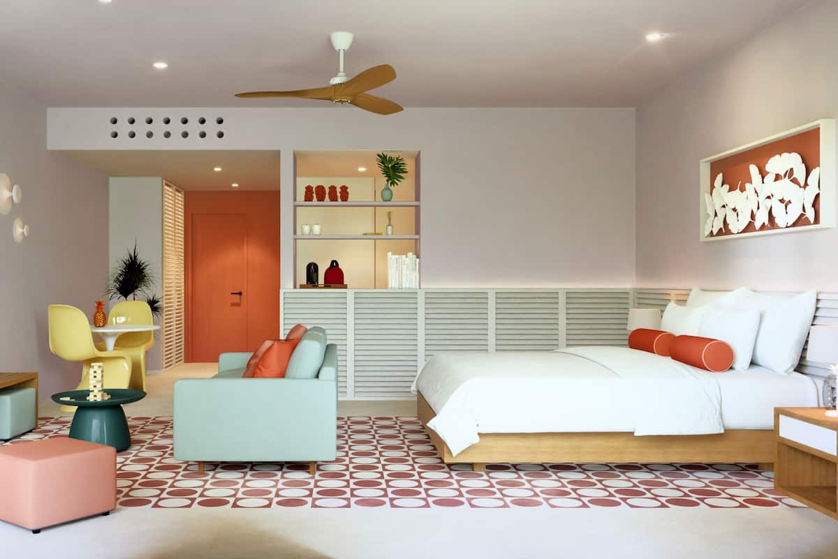 A modern bedroom with a bed, a sofa, a chair, a small table, and a ceiling fan.