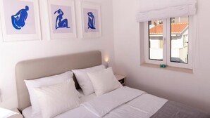 A bedroom with a bed, a nightstand, and three framed artworks on the wall.