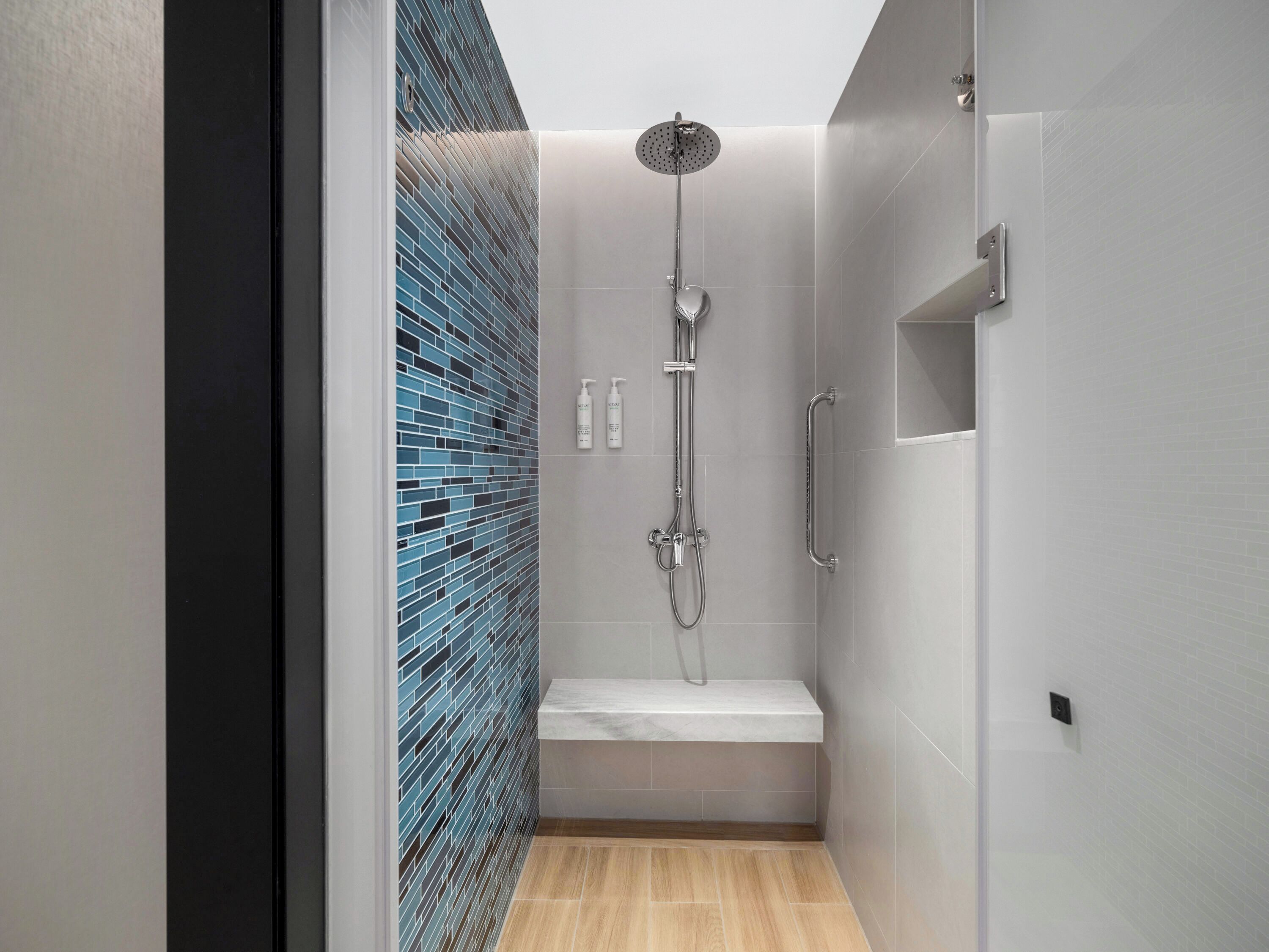 A modern shower with a rain showerhead, handheld showerhead, and a handheld shower attachment.