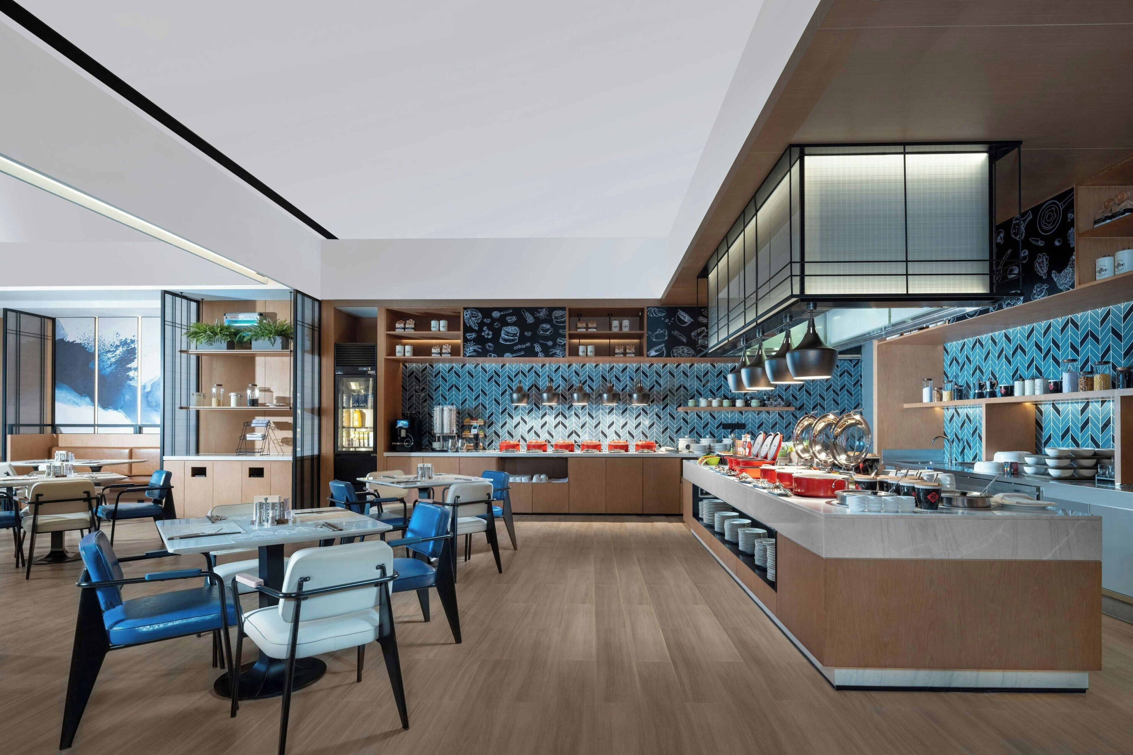 A modern restaurant with a central island, blue patterned backsplash, and wooden flooring.