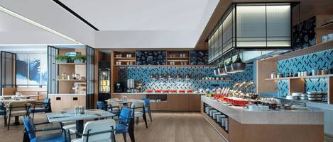 A modern restaurant with a central island, blue patterned backsplash, and wooden flooring.