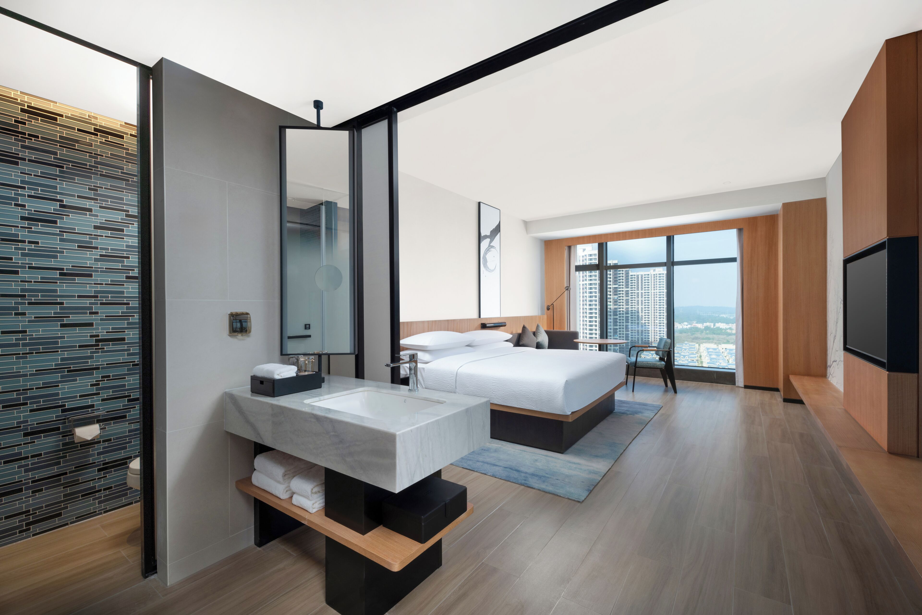 A modern hotel room with a large bed, a bathroom with a marble sink, and a city view.