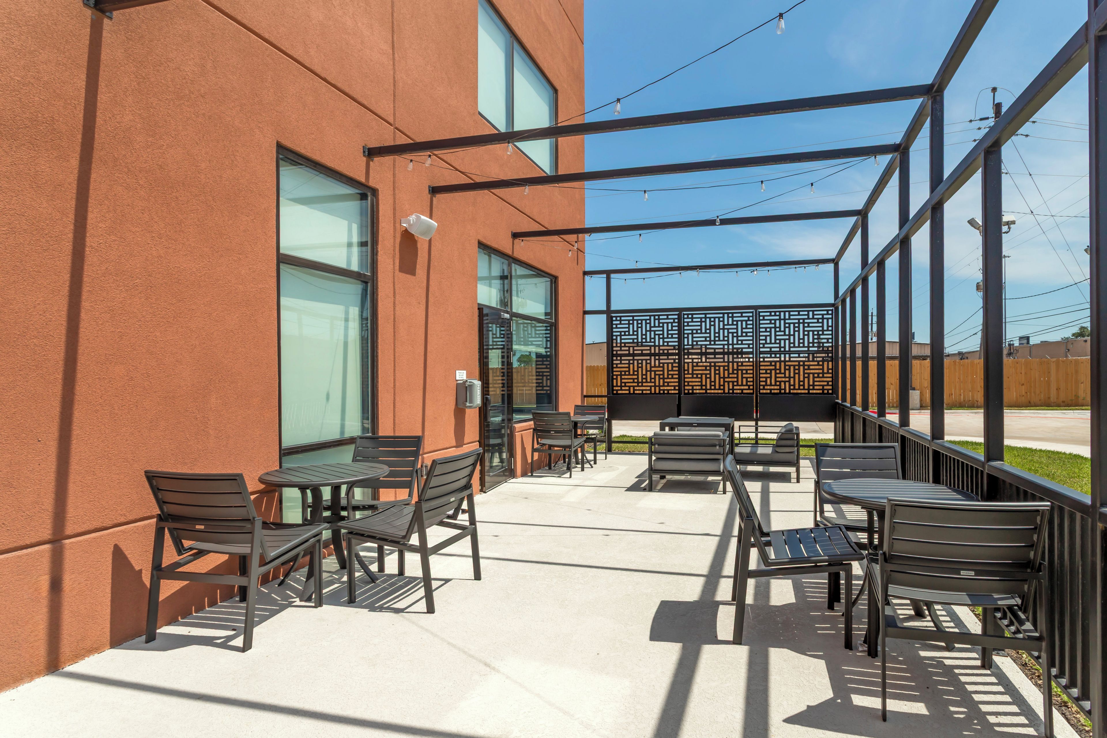 An outdoor patio area with tables and chairs, a security camera, and a decorative fence.