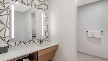 Une salle de bain moderne avec un meuble-lavabo blanc, un grand miroir et un porte-serviettes.