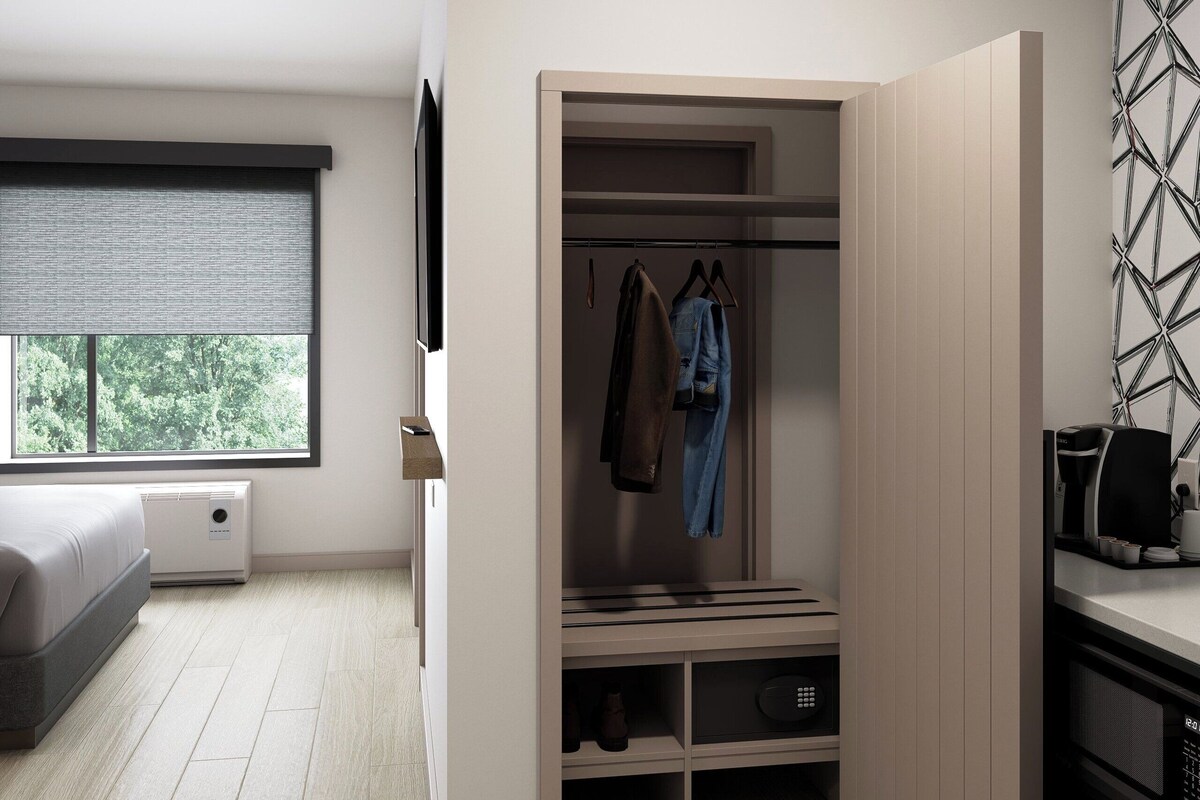 Une chambre moderne avec un lit, un dressing et une fenêtre équipée de stores.