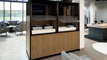 A modern hotel lobby with a reception desk, seating area, and a menu board displaying breakfast options.