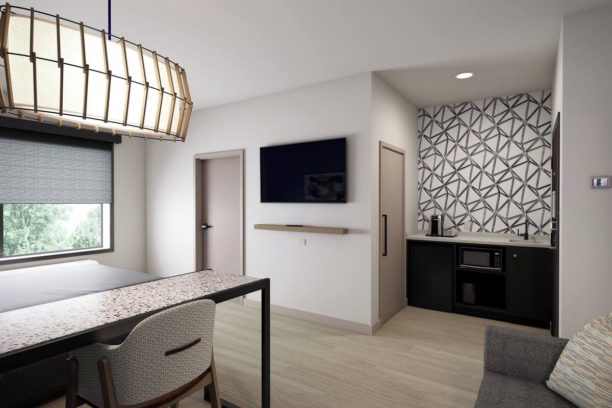 Un espace de vie moderne et compact comprenant un coin repas, une kitchenette et une grande fenêtre.