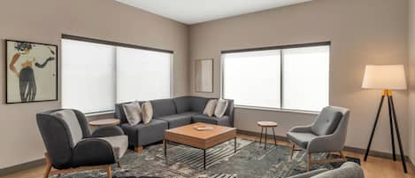 A modern living room with a sectional sofa, armchairs, a coffee table, and a floor lamp.