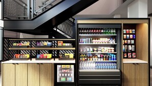 Un espacio comercial moderno con un expositor refrigerado y estantes llenos de aperitivos y bebidas.