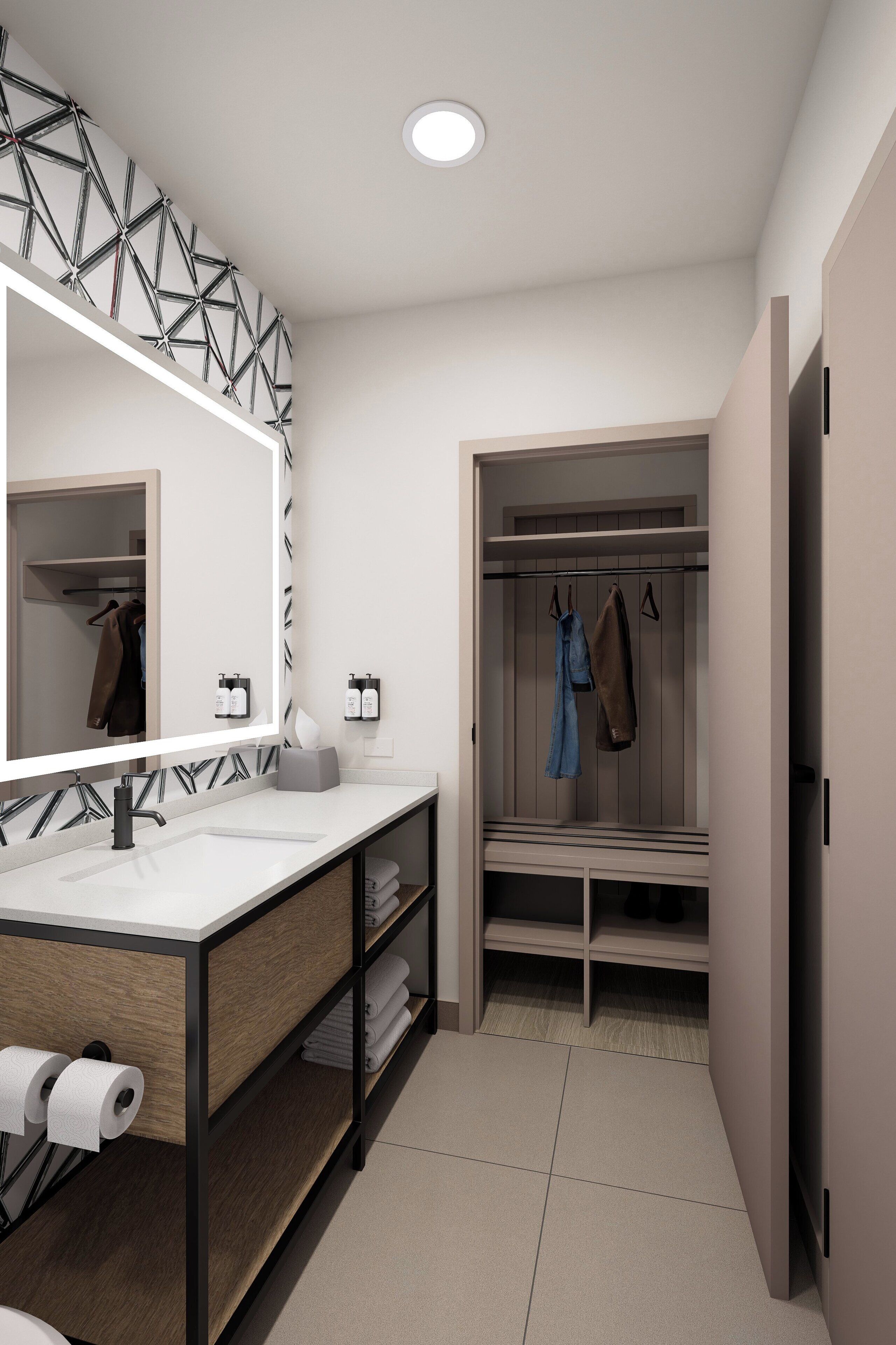 A modern bathroom with a vanity, mirror, and a walk-in closet with hanging clothes.