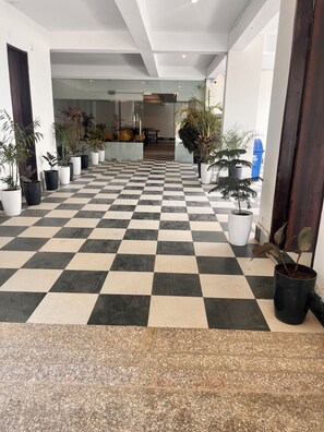 A hotel lobby with a checkered floor, potted plants, and a staircase leading to another level. - Apna Homes Stay and Hotel I Gurugram (Gurugram)