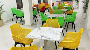 Un comedor con varias mesas y sillas, ventiladores de techo y plantas en macetas.