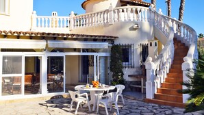 Un bâtiment blanc doté d’un balcon, d’un escalier et d’un patio avec une table et des chaises.