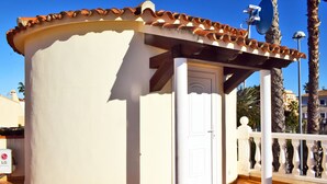 Un bâtiment d’angle à la façade blanche, avec un toit recouvert de tuiles et une porte blanche.