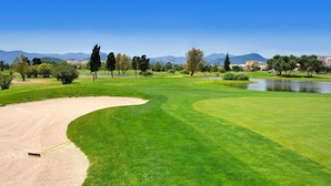 Un parcours de golf bien entretenu, doté d’un bunker de sable, d’obstacles d’eau et offrant une vue dégagée sur les montagnes lointaines.