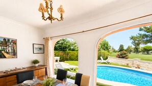 Un comedor con vistas a una piscina, un candelabro y mobiliario de exterior.