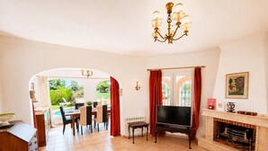 Una sala de estar con televisor, chimenea, comedor y vistas al jardín.