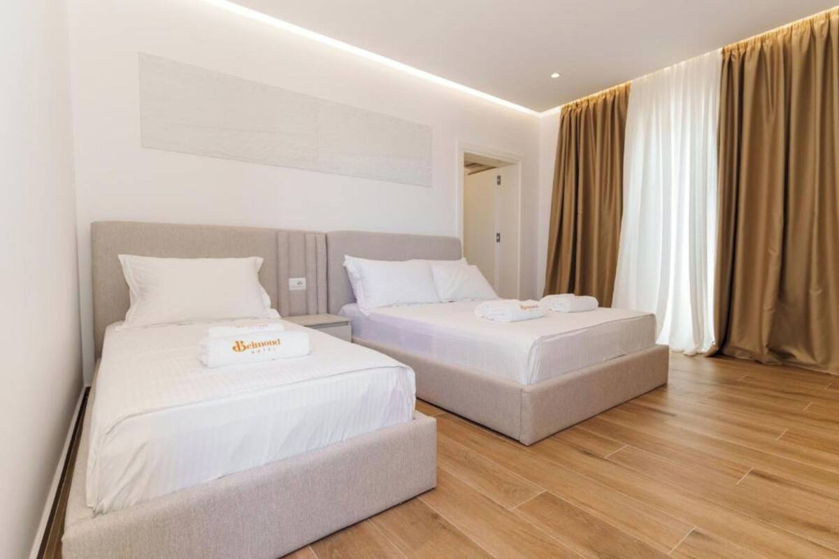 Habitación de hotel con dos camas, una paleta de colores neutros y suelo de madera.
