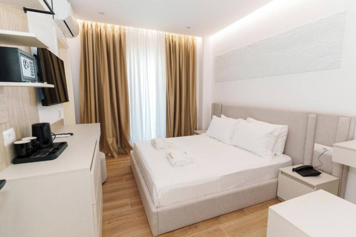 Una habitación de hotel moderna con una cama, una mesita de noche y un escritorio con cafetera.