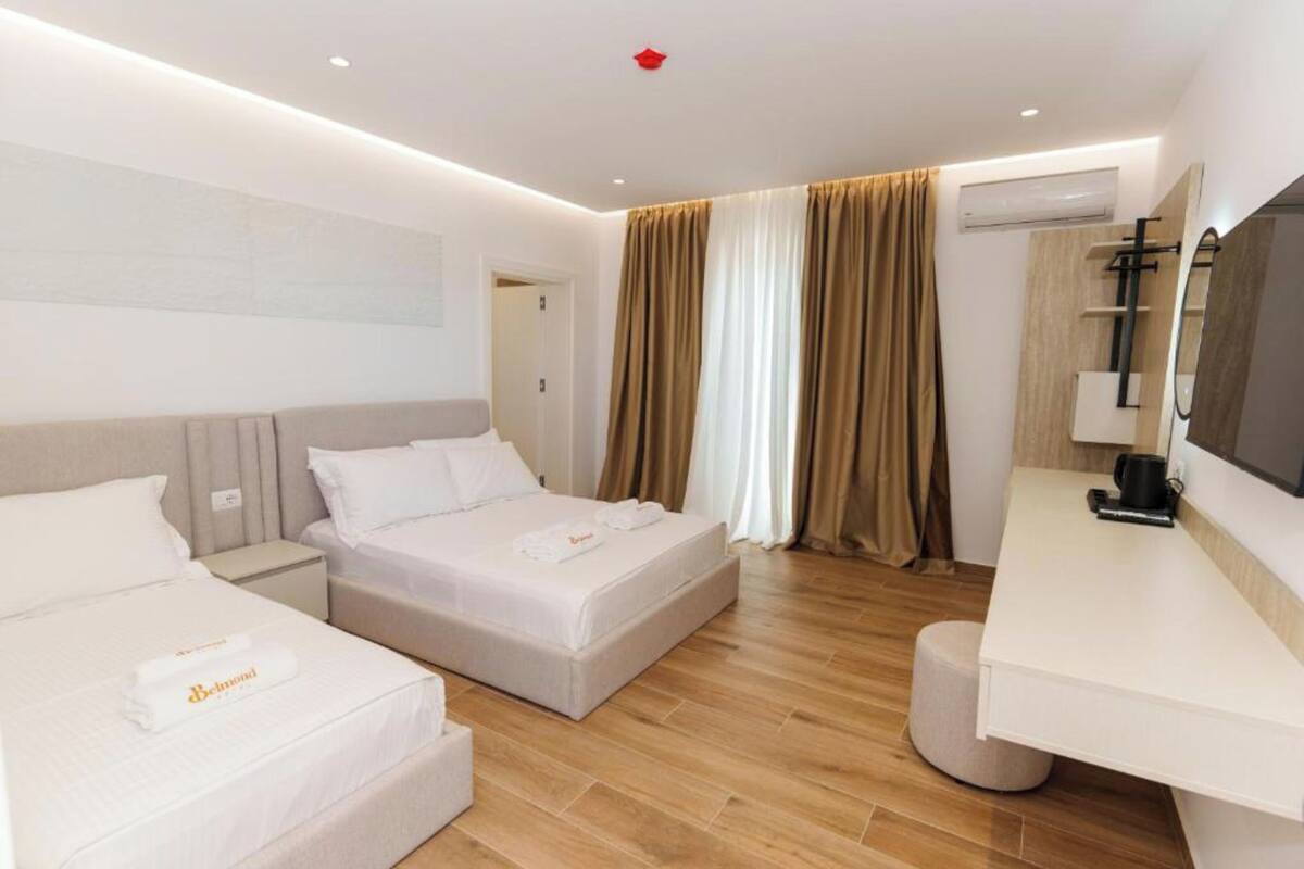 Una habitación de hotel moderna con dos camas, un escritorio y un espejo grande.