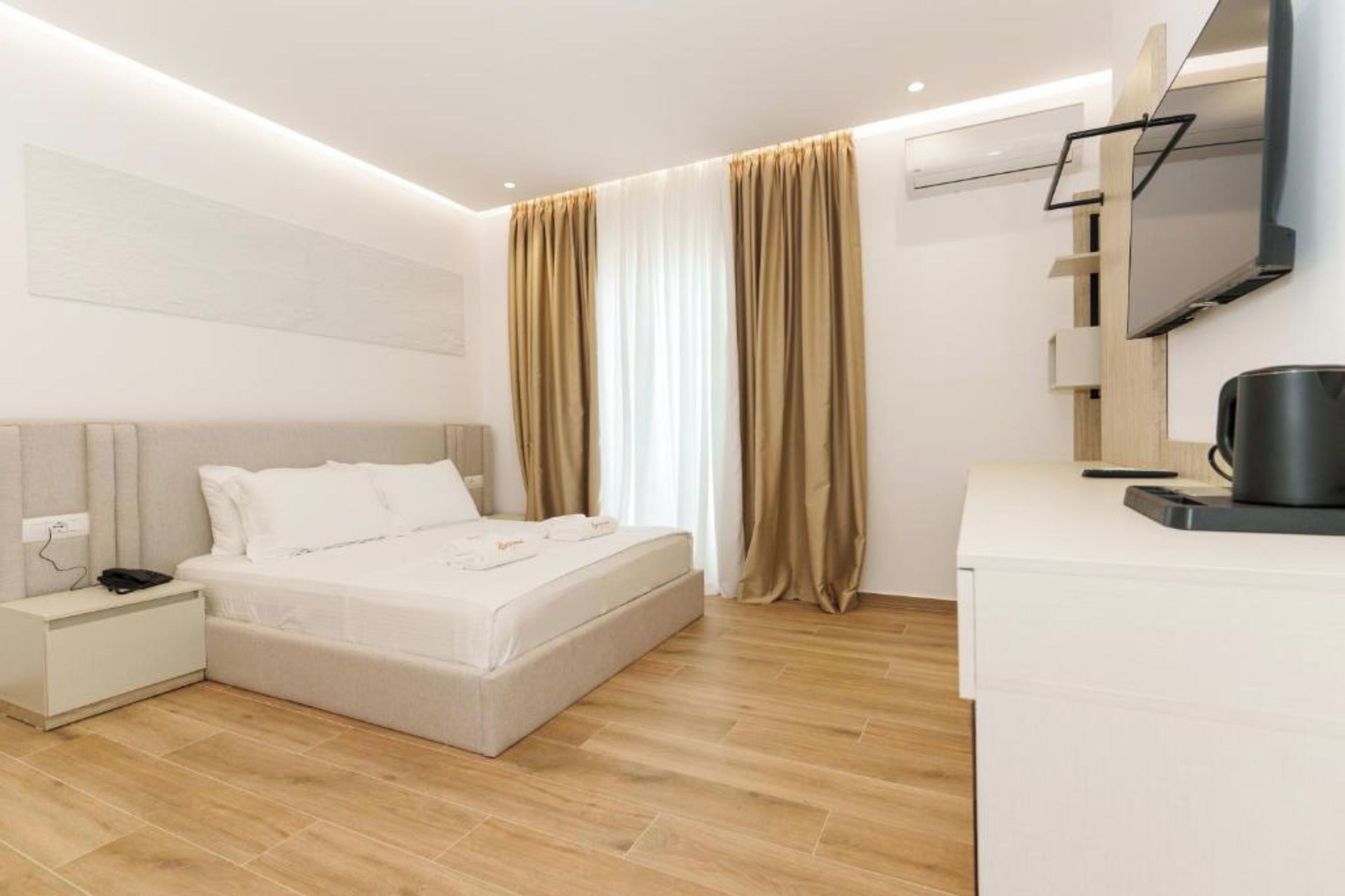 Une chambre d’hôtel moderne équipée d’un lit, d’une table de chevet et d’un téléviseur à écran plat fixé au mur.