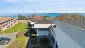 Un edificio moderno con tejado plano, zona de estacionamiento y vista al mar.