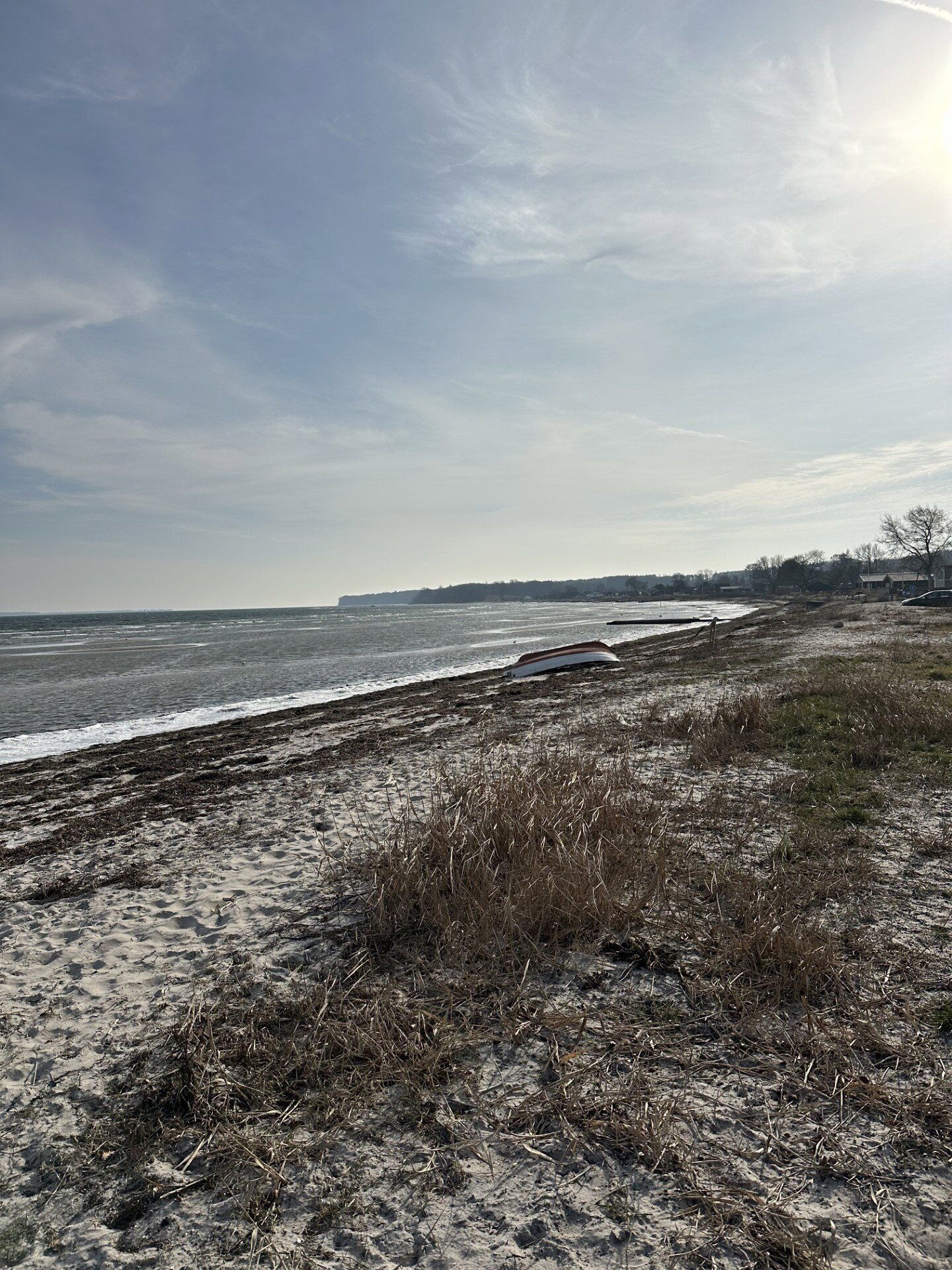 Une plage avec un rivage sablonneux, un bateau et une côte lointaine.