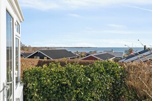 Un barrio residencial con casas, un seto y vista al mar.