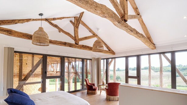 A bedroom with a large bed, wooden beams, large windows, and a view of the countryside. - In the heart of the Gers countryside, discover the Gîte Laborde (Monpardiac)