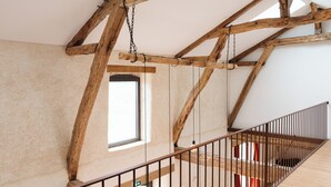 A spacious attic room with exposed wooden beams, a wooden staircase, and a skylight. - In the heart of the Gers countryside, discover the Gîte Laborde (Monpardiac)
